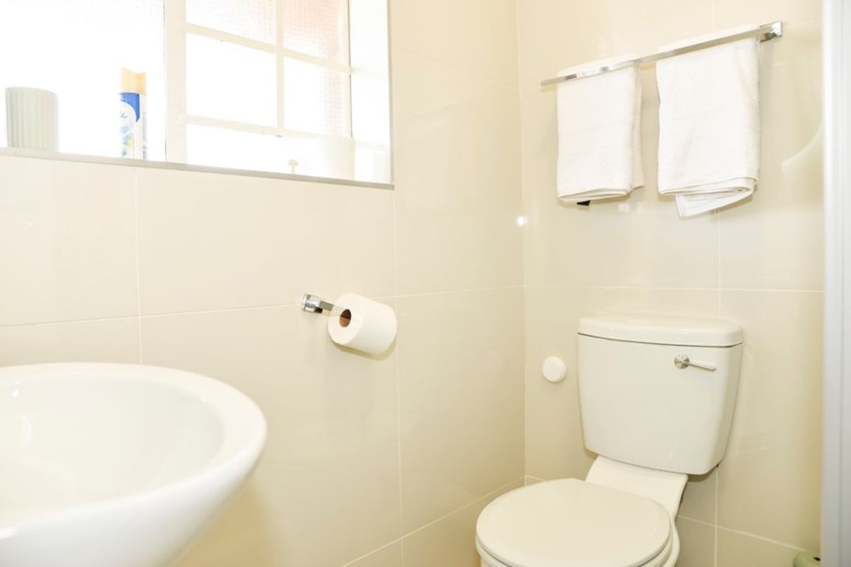 A compact bathroom featuring tiled walls, a standard toilet, and a wall-mounted washbasin.