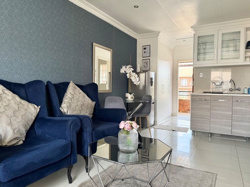 An open-plan living and kitchen area featuring modern cabinetry, tiled flooring, and a feature wall with decorative wallpaper.