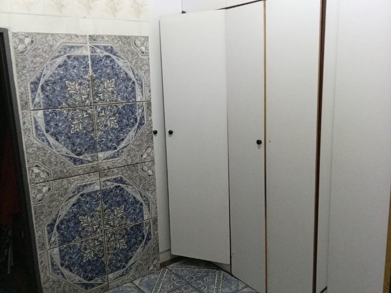 A bedroom featuring built-in cupboards with white cabinetry and patterned ceramic floor and wall tiling.