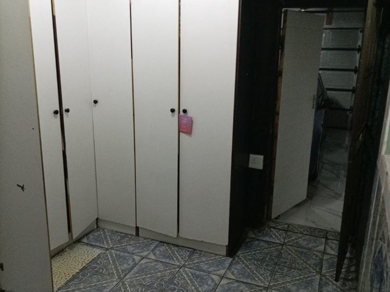A utility space featuring extensive built-in white cabinetry and patterned tiled flooring, providing ample storage capacity.