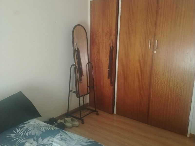 A bedroom featuring built-in wooden cupboards and laminate flooring, offering functional storage space.