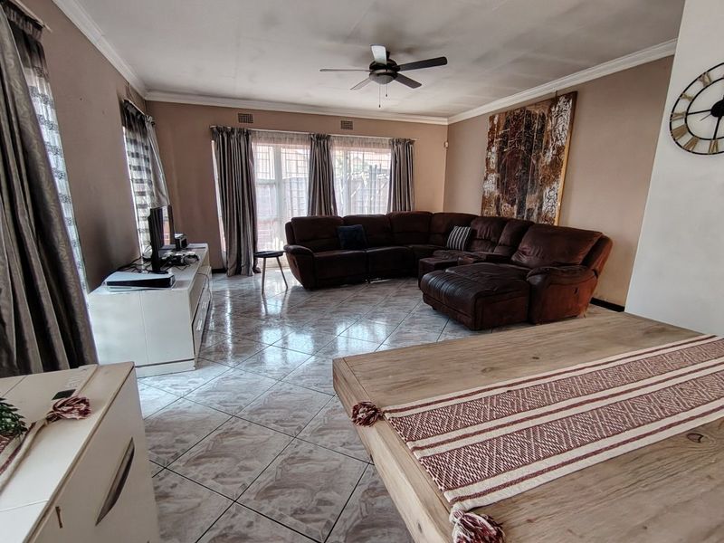 Spacious living room featuring tiled flooring, a ceiling fan, and large windows allowing natural light.