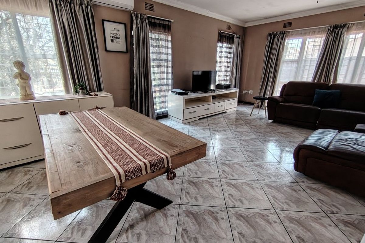 Spacious living room featuring tiled flooring, a ceiling fan, and a wall-mounted air conditioning unit.