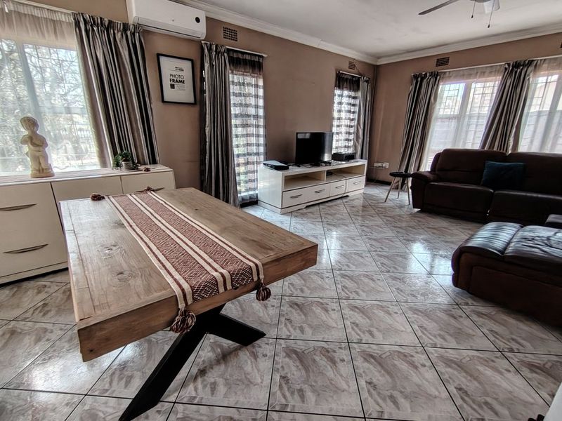 Spacious living room featuring tiled flooring, a ceiling fan, and a wall-mounted air conditioning unit.