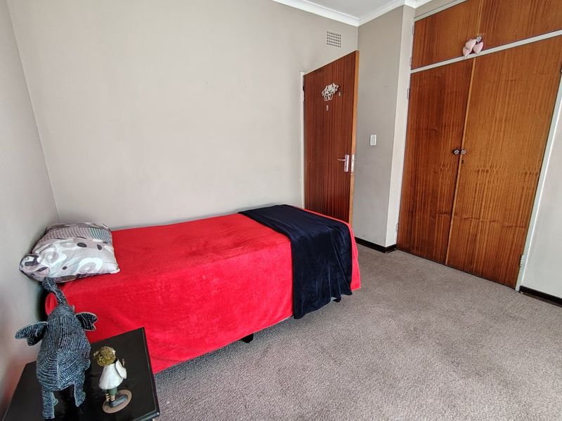 A bedroom featuring built-in wooden cupboards, neutral wall finishes, and carpeted flooring.