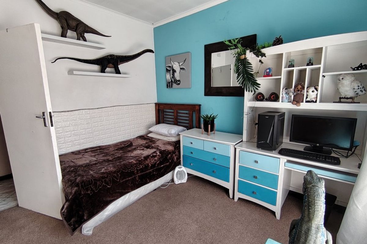 A bedroom featuring carpeted flooring, textured wall paneling, and built-in shelving units.