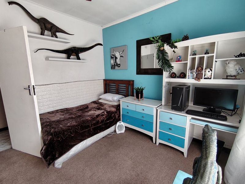 A bedroom featuring carpeted flooring, textured wall paneling, and built-in shelving units.