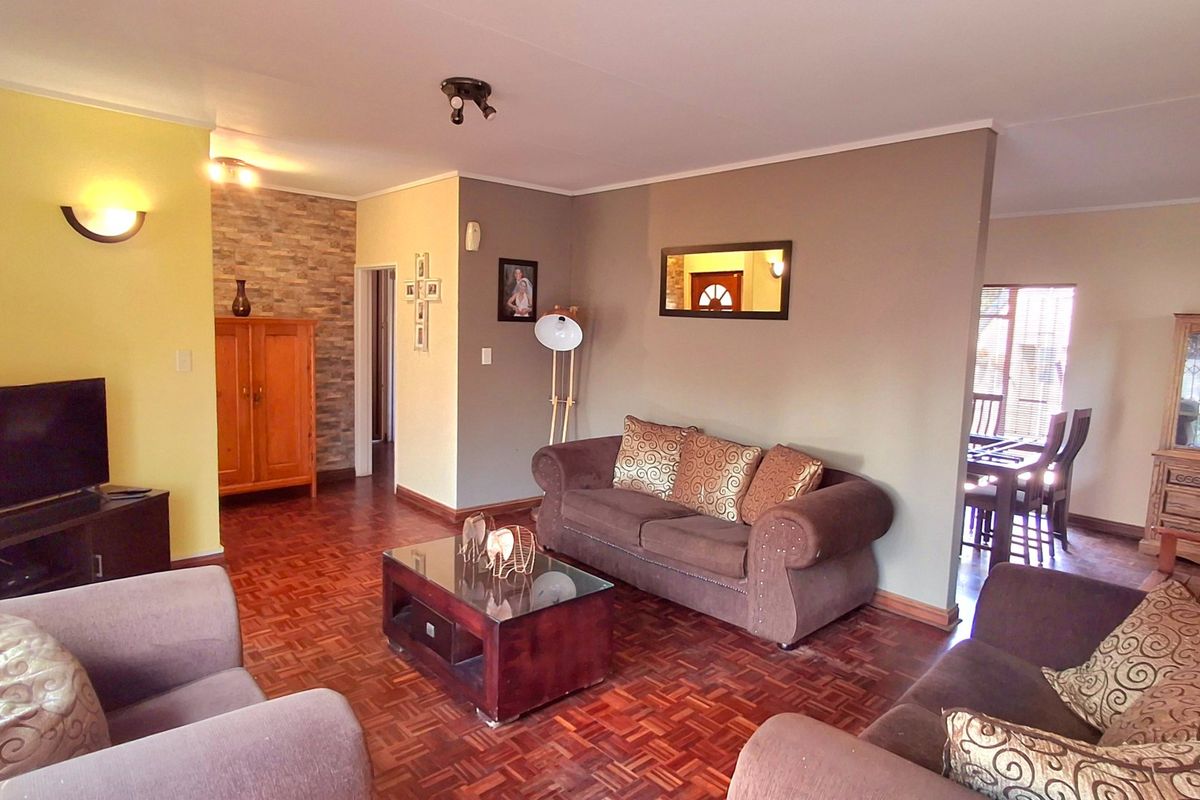 A spacious living room featuring classic parquet flooring, a textured stone accent wall, and warm ambient lighting.