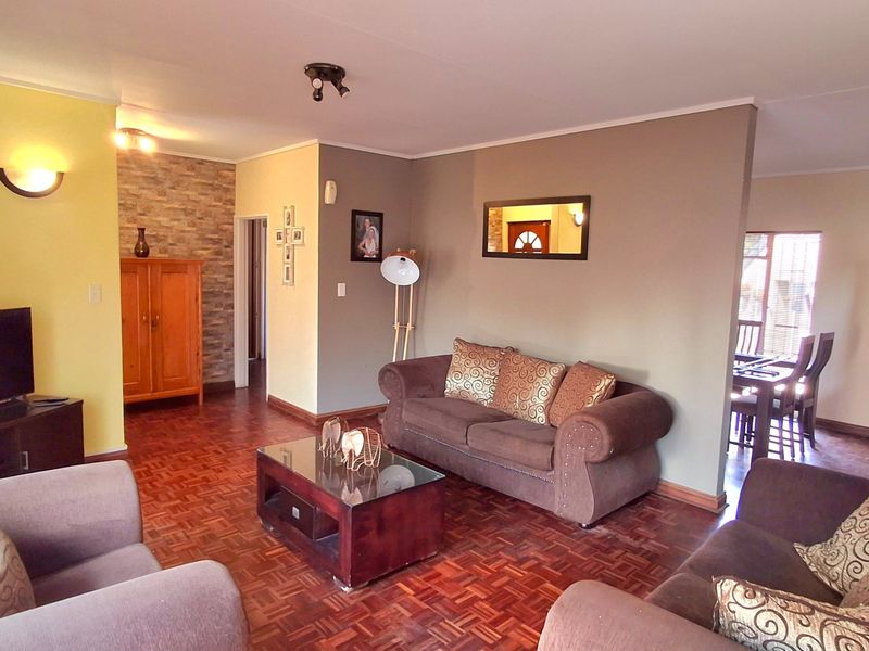 A spacious living room featuring classic parquet flooring, a textured stone accent wall, and warm ambient lighting.