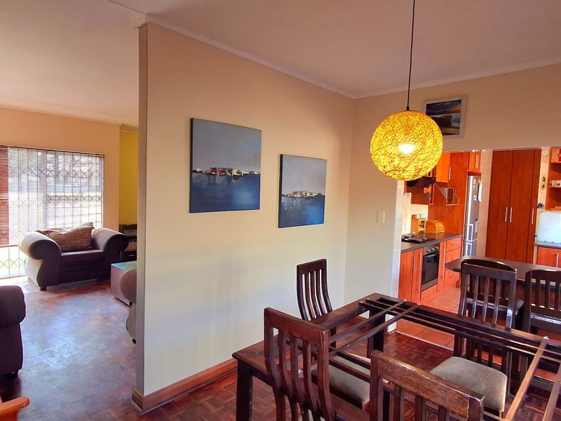 Open-plan living and dining area featuring parquet flooring, flowing into a functional kitchen with built-in cabinetry and integrated appliances.