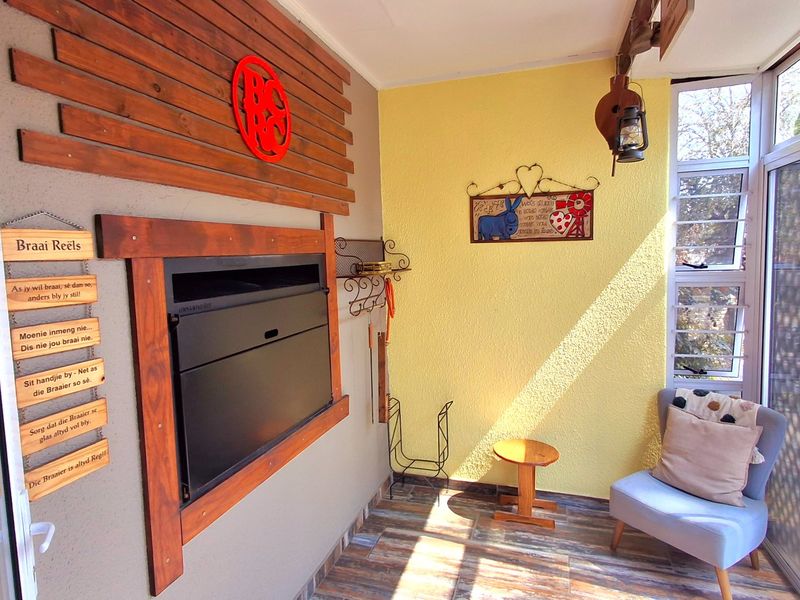 Enclosed patio area featuring a built-in braai, wood-paneled accent wall, tiled flooring, and large sliding glass doors providing natural light.