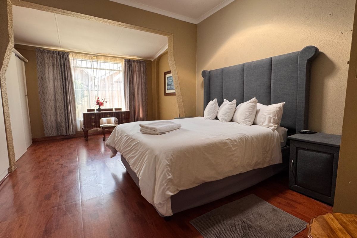 Spacious bedroom featuring laminate flooring, built-in cupboards, and a coved ceiling, offering a comfortable and functional living space.