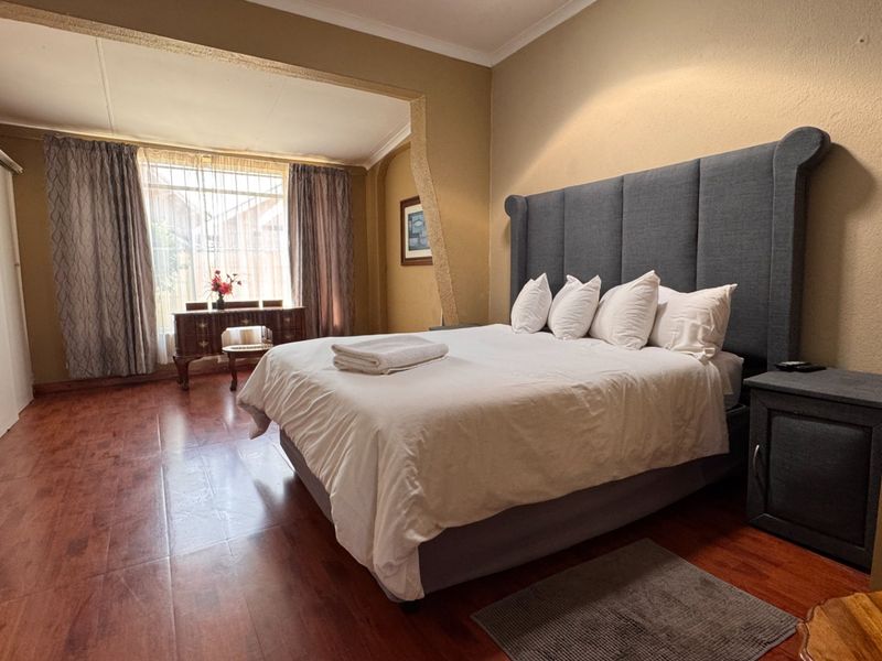 Spacious bedroom featuring laminate flooring, built-in cupboards, and a coved ceiling, offering a comfortable and functional living space.