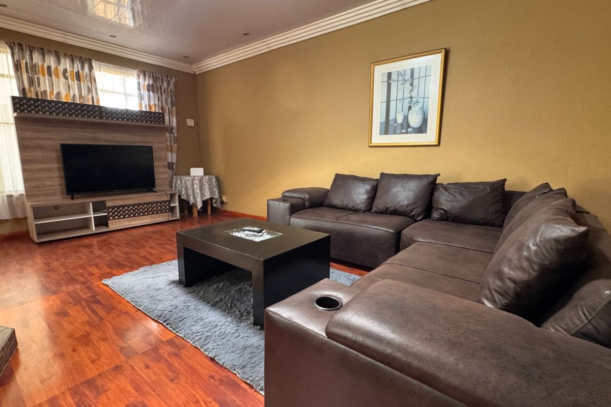 A living room featuring laminate flooring, coved ceilings, recessed lighting, and a fireplace hearth, providing a comfortable and functional space.