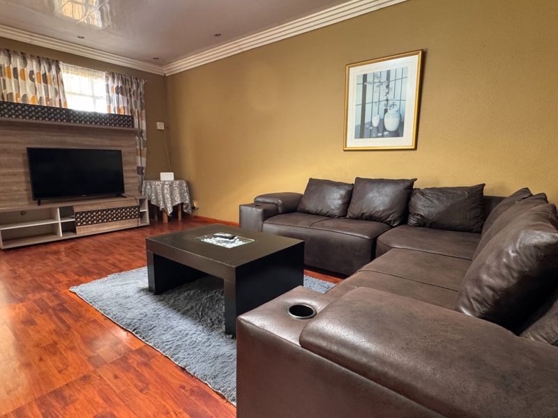 A living room featuring laminate flooring, coved ceilings, recessed lighting, and a fireplace hearth, providing a comfortable and functional space.