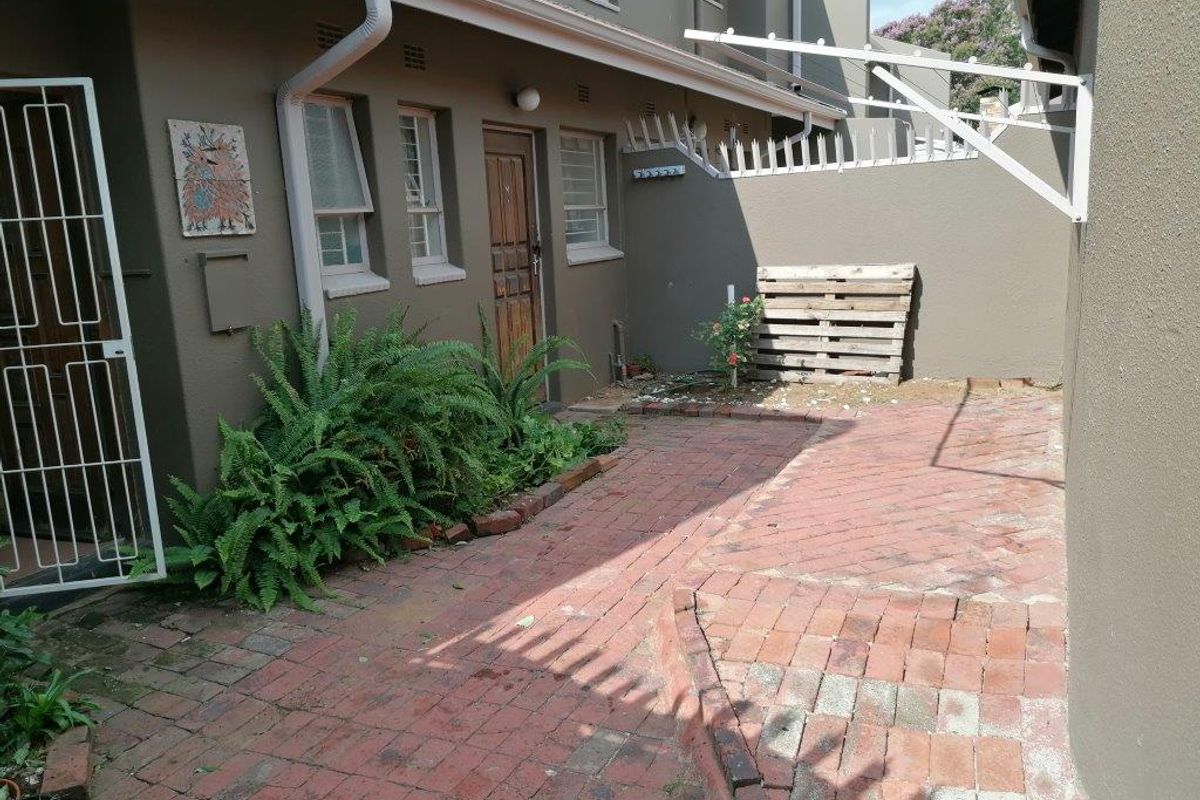 A rear courtyard area featuring brick paving, a wall-mounted washing line, and direct access to the townhouse via a security gate.