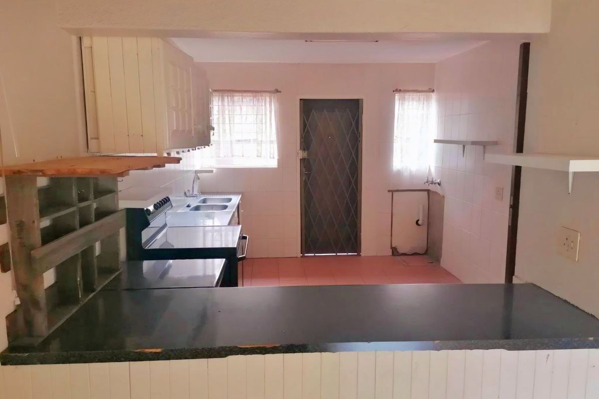 A functional, empty kitchen featuring a double sink, freestanding stove, and tiled splashbacks, offering a blank canvas for modern renovation and design updates.