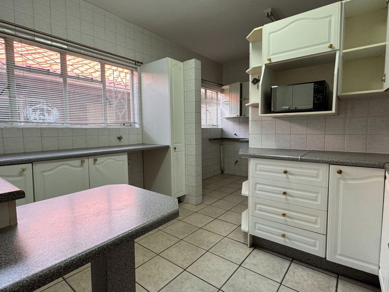 A functional kitchen featuring tiled walls and floors, ample built-in cabinetry, laminate countertops, and a built-in oven, offering a clean and practical workspace.