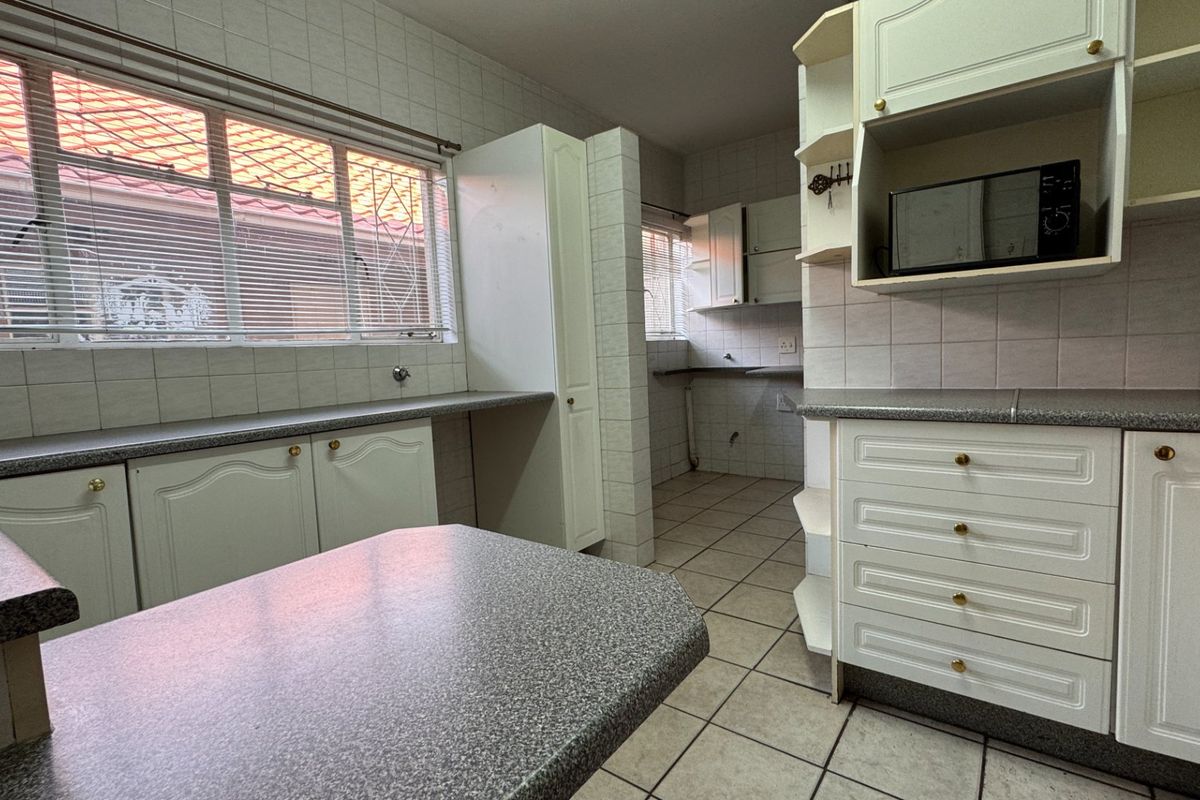 A functional kitchen featuring ample built-in cabinetry, laminate countertops, and tiled finishes, offering a blank canvas for modern renovation and design updates.