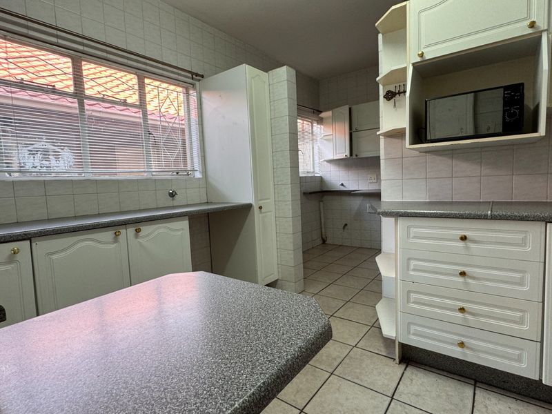 A functional kitchen featuring ample built-in cabinetry, laminate countertops, and tiled finishes, offering a blank canvas for modern renovation and design updates.