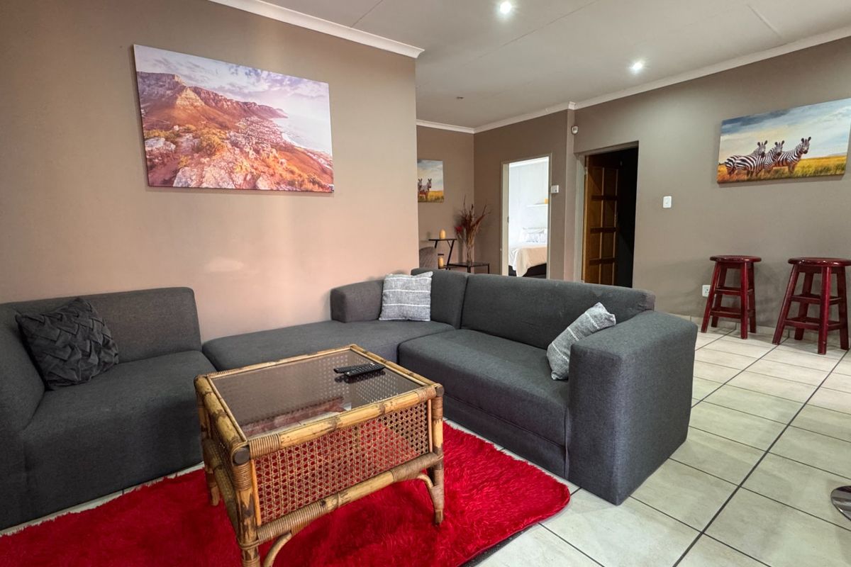 A living room featuring neutral wall tones, ceramic floor tiles, and recessed downlighting, providing a functional and comfortable space for relaxation.