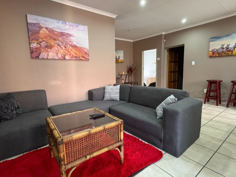 A living room featuring neutral wall tones, ceramic floor tiles, and recessed downlighting, providing a functional and comfortable space for relaxation.