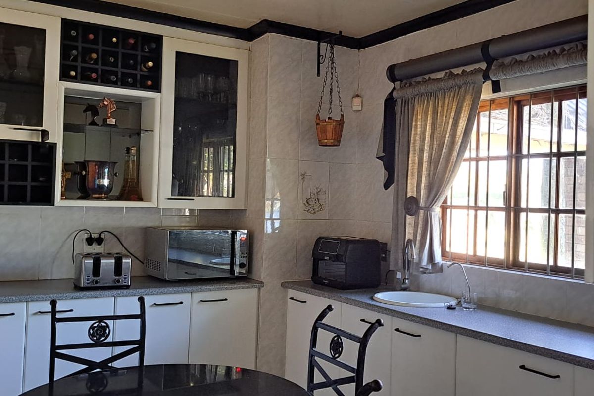 A functional kitchen featuring white built-in cabinetry, laminate countertops, a tiled backsplash, and integrated wine storage with glass-front display cabinets.