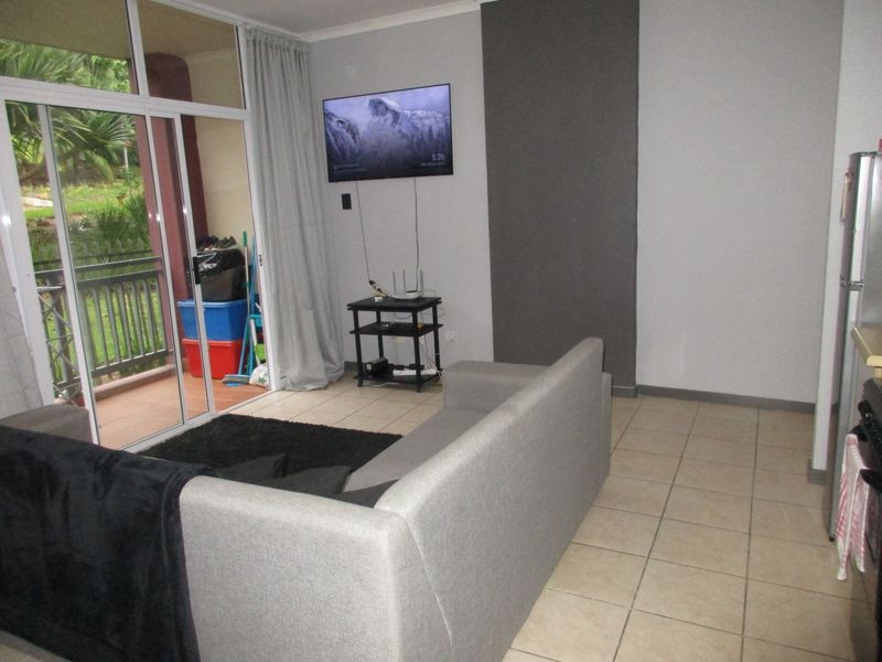 Open plan living area featuring tiled flooring and direct access to a private balcony through large sliding glass doors.