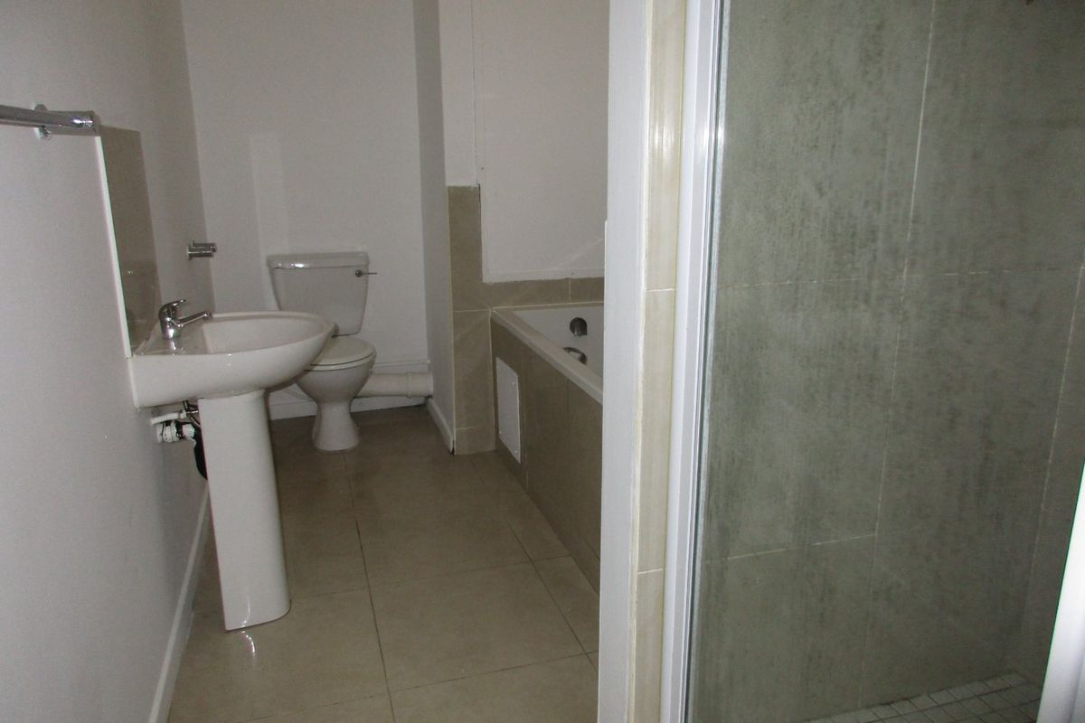 A functional bathroom featuring a pedestal basin, toilet, bathtub, and a separate shower enclosure with tiled finishes.