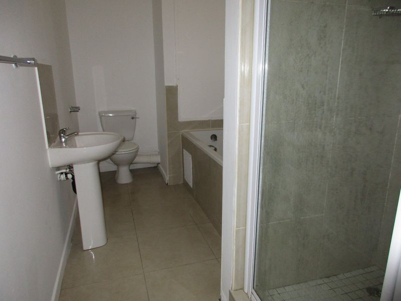 A functional bathroom featuring a pedestal basin, toilet, bathtub, and a separate shower enclosure with tiled finishes.
