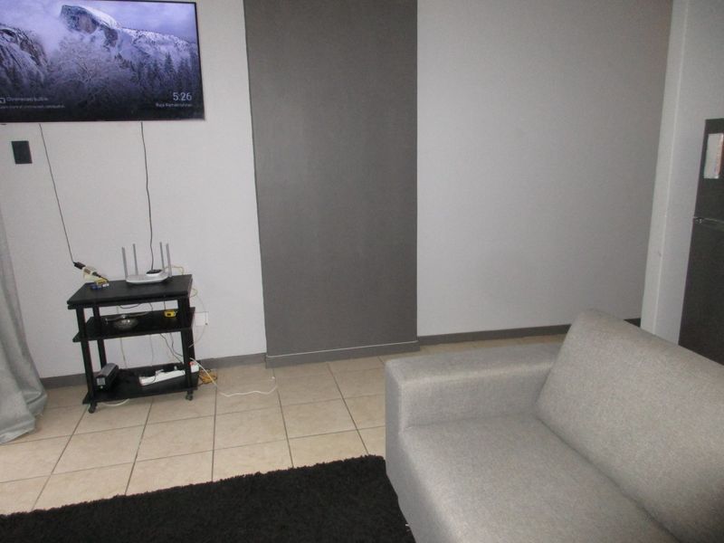 A living room area featuring tiled flooring and a grey accent wall, providing a neutral base for interior design.
