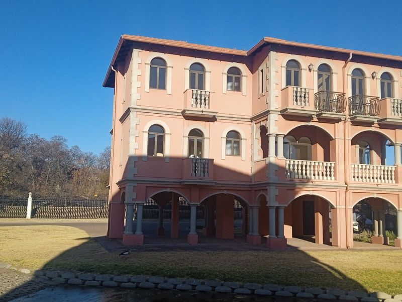 A three-story residential building featuring Mediterranean-style architecture with arched windows, multiple balconies, and a covered ground-level colonnade.