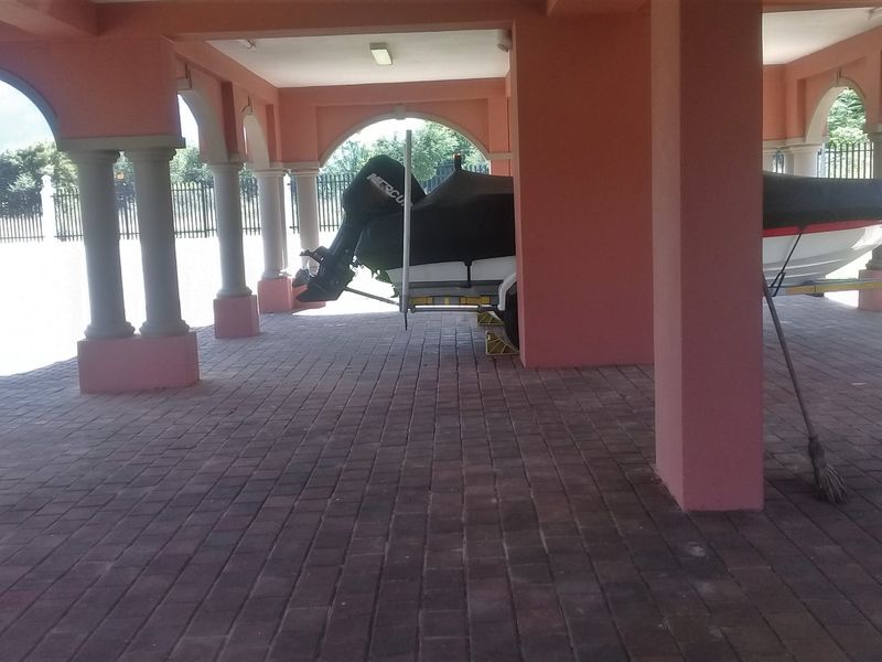 A spacious, covered outdoor garage area featuring paved flooring and decorative arched columns, providing ample sheltered parking space.