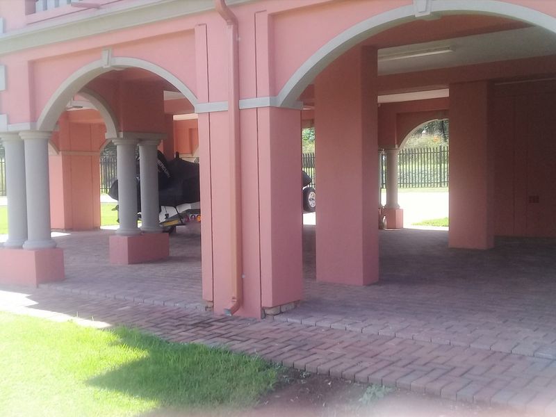 A spacious, covered parking area featuring architectural arched columns and durable paved flooring, providing ample space for multiple vehicles.