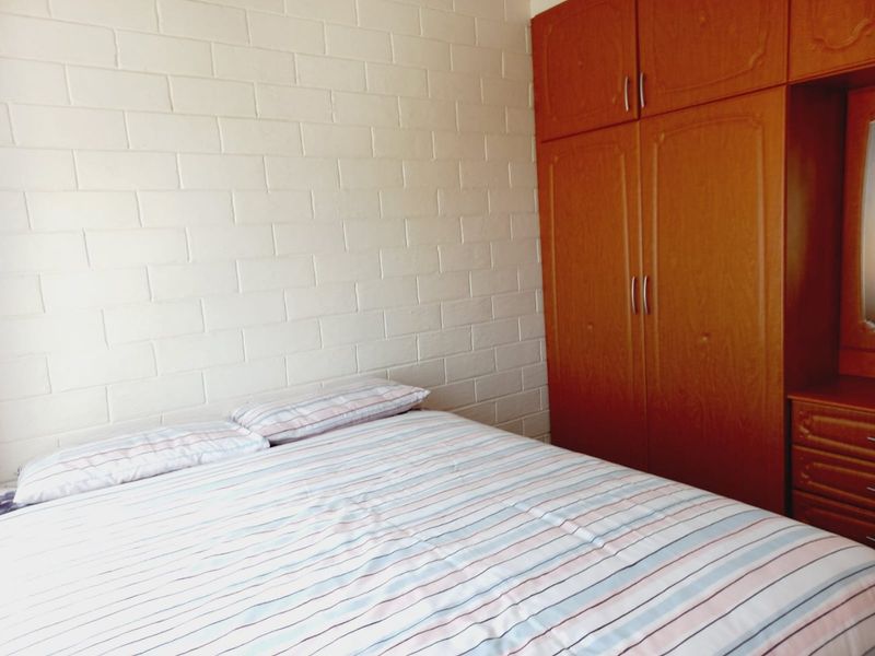 A bedroom featuring a built-in wooden wardrobe and a painted exposed brick wall.