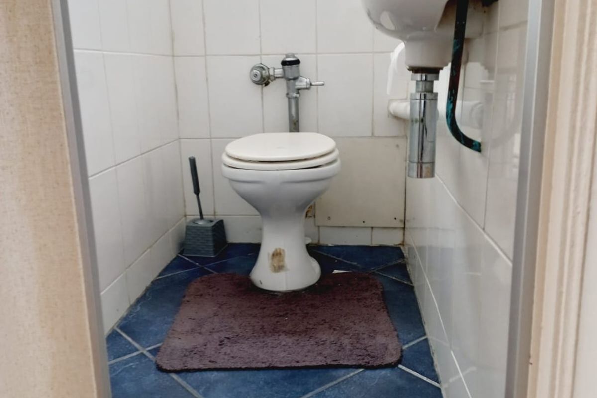 A compact guest bathroom featuring a wall-mounted basin and a flush valve toilet with tiled finishes.