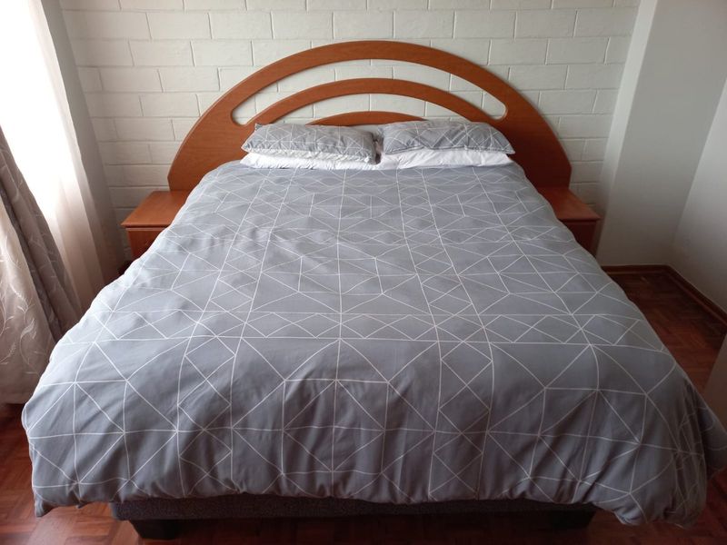 A bedroom featuring parquet flooring and a painted brick feature wall, providing a neutral foundation for interior design.