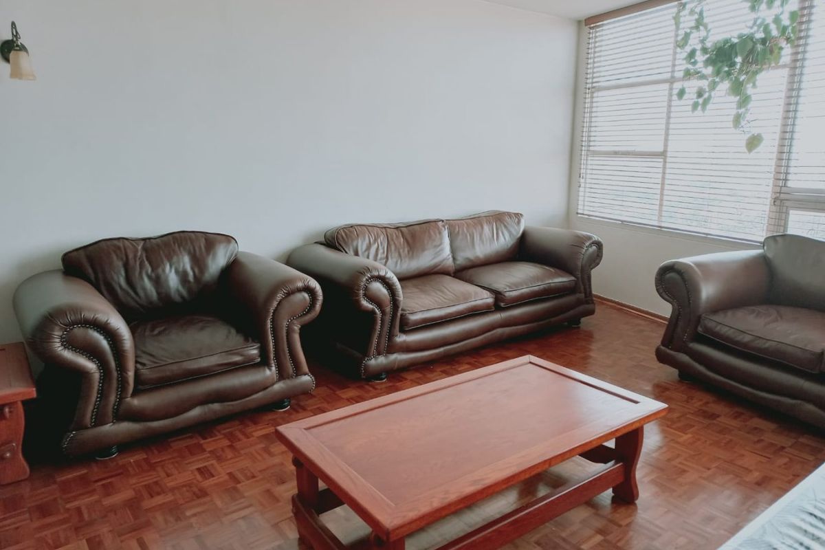 A living room featuring classic parquet flooring and large windows fitted with venetian blinds, offering a neutral space ready for modern updates.