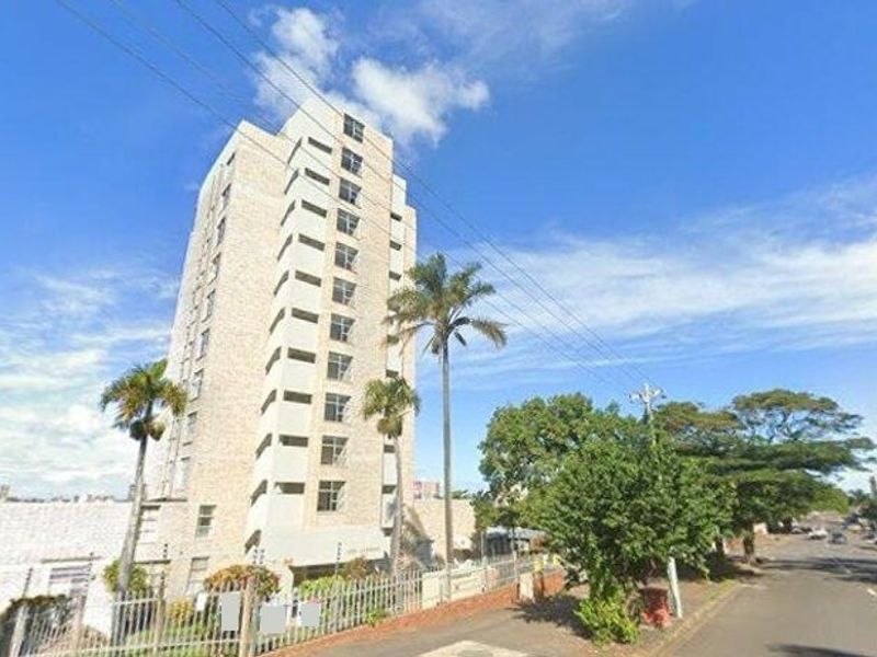 Exterior view of a multi-story apartment building featuring a brick facade and secure perimeter fencing.