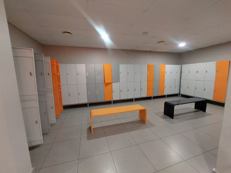 A commercial locker room featuring rows of built-in storage lockers, tiled flooring, and recessed ceiling lighting.