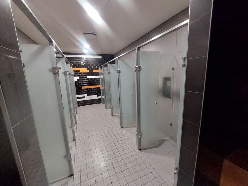 Commercial bathroom facility featuring multiple individual cubicles with frosted glass doors and modern tiled finishes.