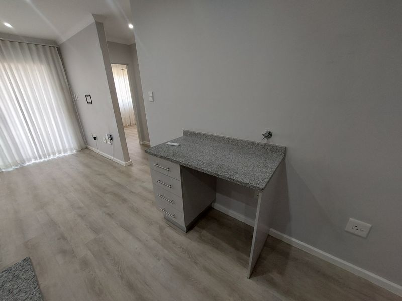 A clean, modern utility space or study nook featuring a built-in desk with granite countertop and light laminate flooring.