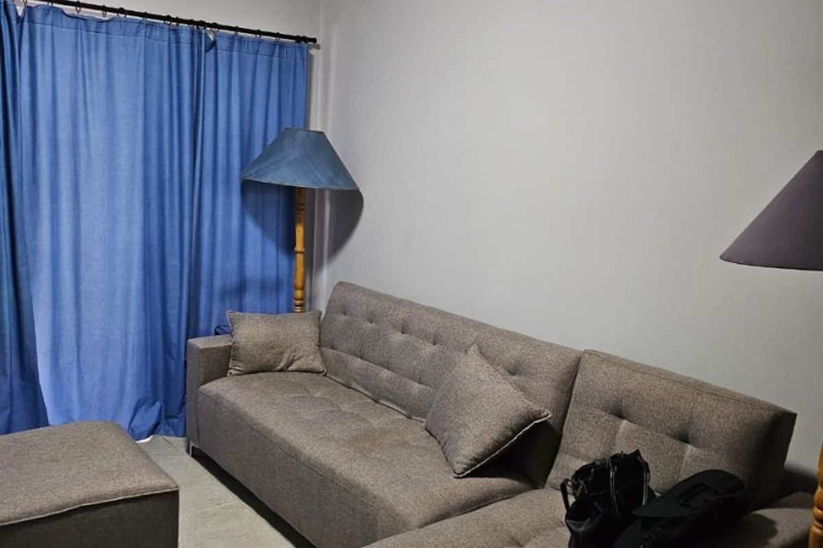 A living room area featuring neutral tiled flooring and a simple, functional layout.