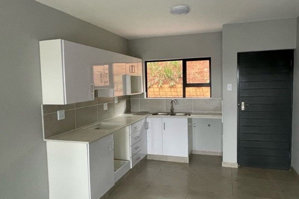 A clean, modern kitchen featuring white built-in cabinetry, tiled backsplash, and neutral floor tiles, offering a functional and bright workspace.