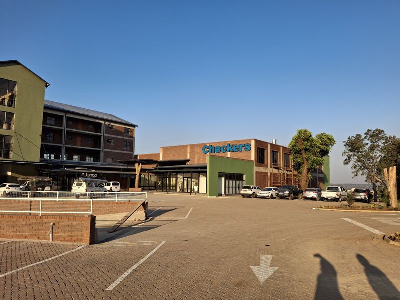 Exterior view of a commercial apartment and retail complex featuring a paved parking area and brick building facade.