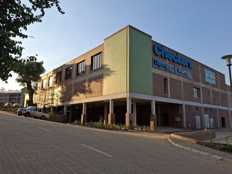 Exterior view of a modern commercial building featuring brick facade, covered parking, and prominent retail signage.
