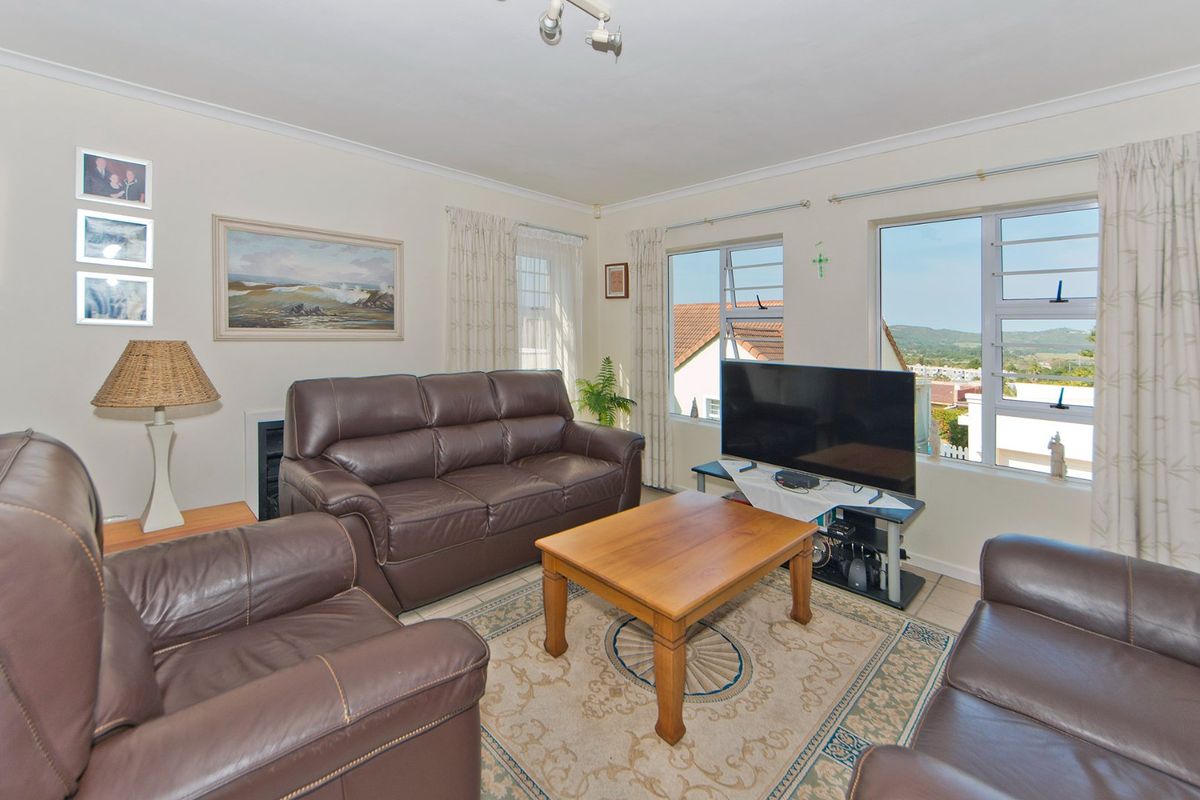 A comfortable living room featuring tiled flooring, a built-in fireplace, and large windows that provide natural light and views of the surrounding area.