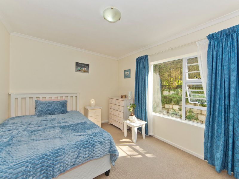 A well-lit bedroom featuring neutral walls, carpeted flooring, and a large window with views of the garden.