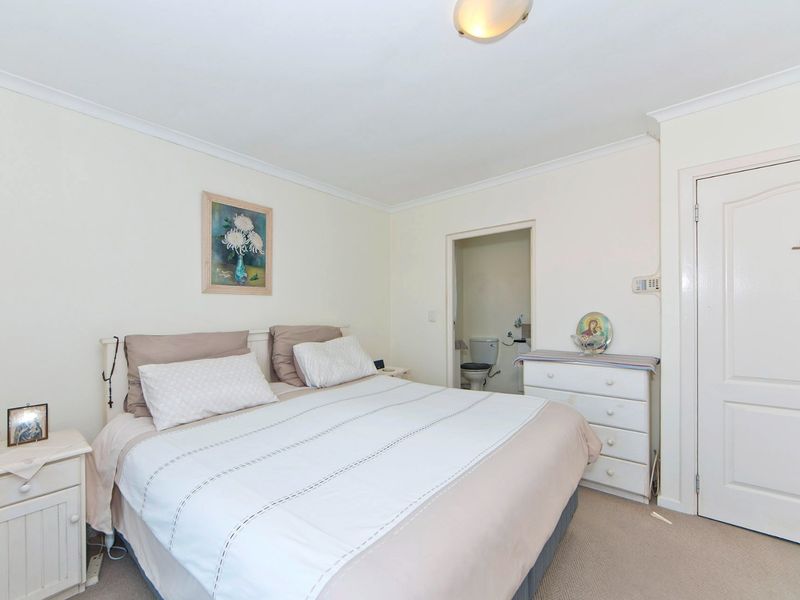 A well-maintained bedroom featuring neutral walls, carpeted flooring, and an adjoining en-suite bathroom.