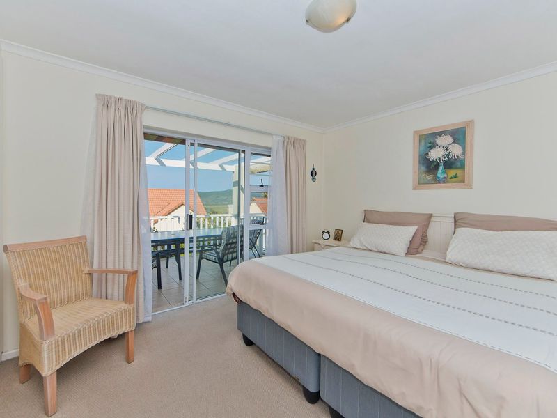 A well-lit bedroom featuring neutral carpeting, a built-in cupboard, and sliding glass doors that open onto a private balcony with scenic views.